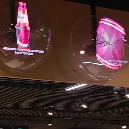 Etalage reclame met 3D holografische voorstelling van een bierflesje en een bierblikje. De hologrammen gemonteerd in doorschijnende halve plexi bollen.
